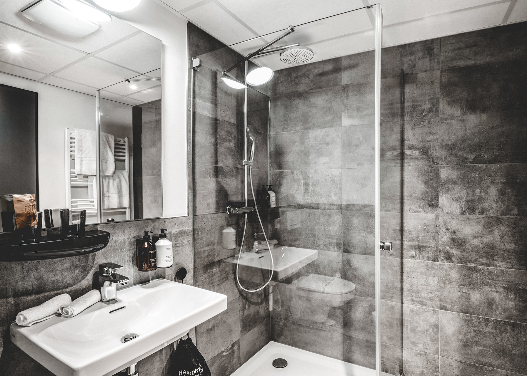 Modernes Apartment-Bad mit grauen Fließen und Regendusche und dunklen Fliesen in einer Unterkunft in Herzogenaurach