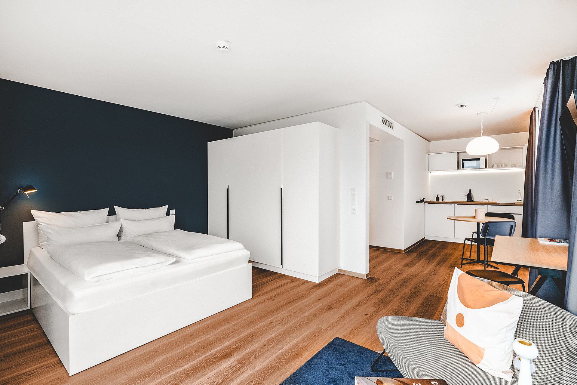 Apartment in Unterkunft in Herzogenaurach mit dunkler Akzentwand, weißem Schrank und offener Küchenzeile