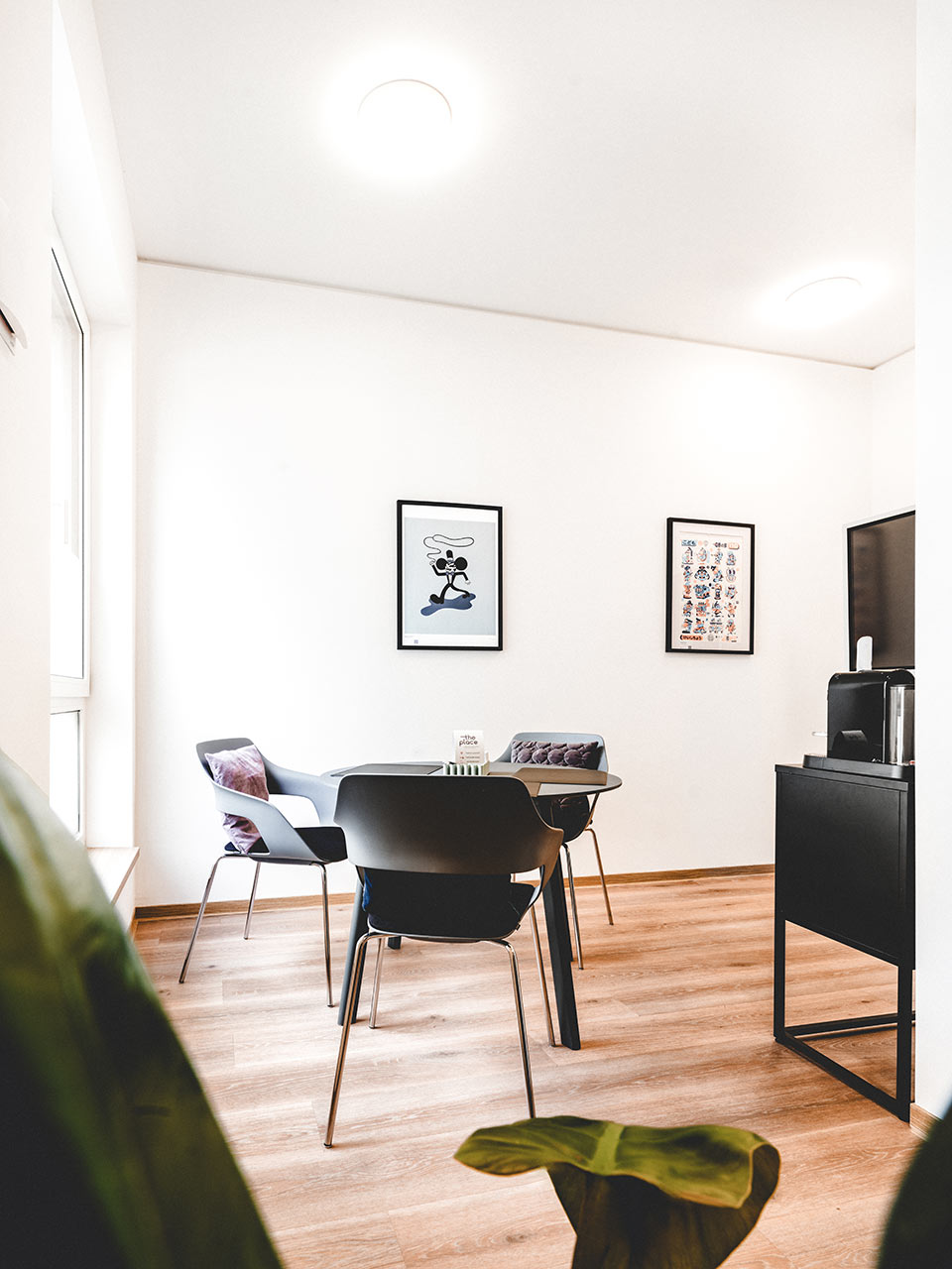 Coworking Space mit rundem Tisch, Kunstdrucken und Kaffeestation
