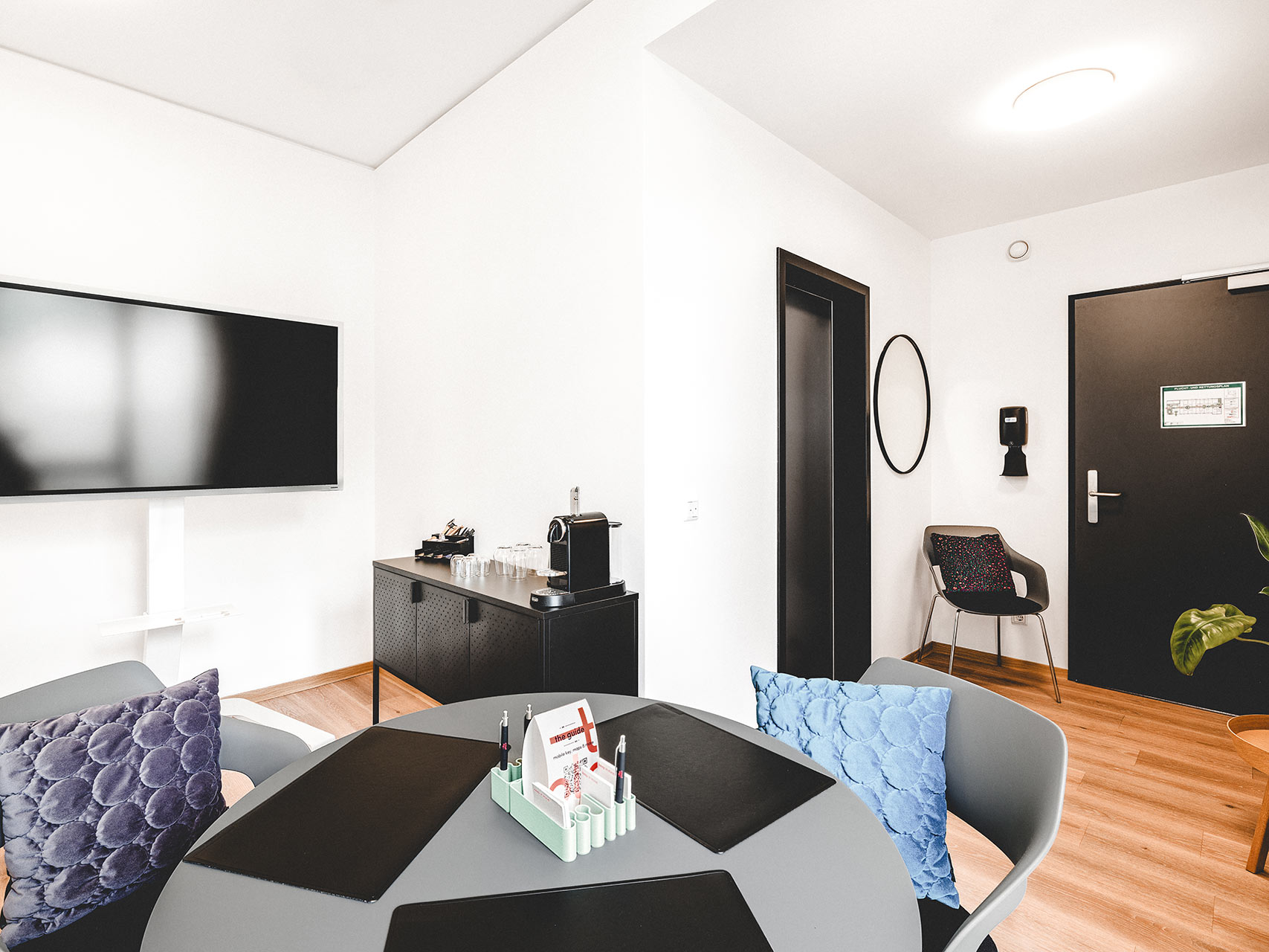 Coworking Space mit rundem Tisch, TV-Bildschirm und Kaffeestation