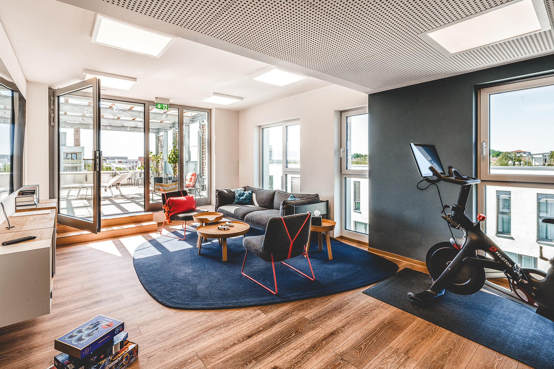 Aufenthaltsbereich mit Terrassenzugang, gemütlichem Sofa und Peloton-Bike