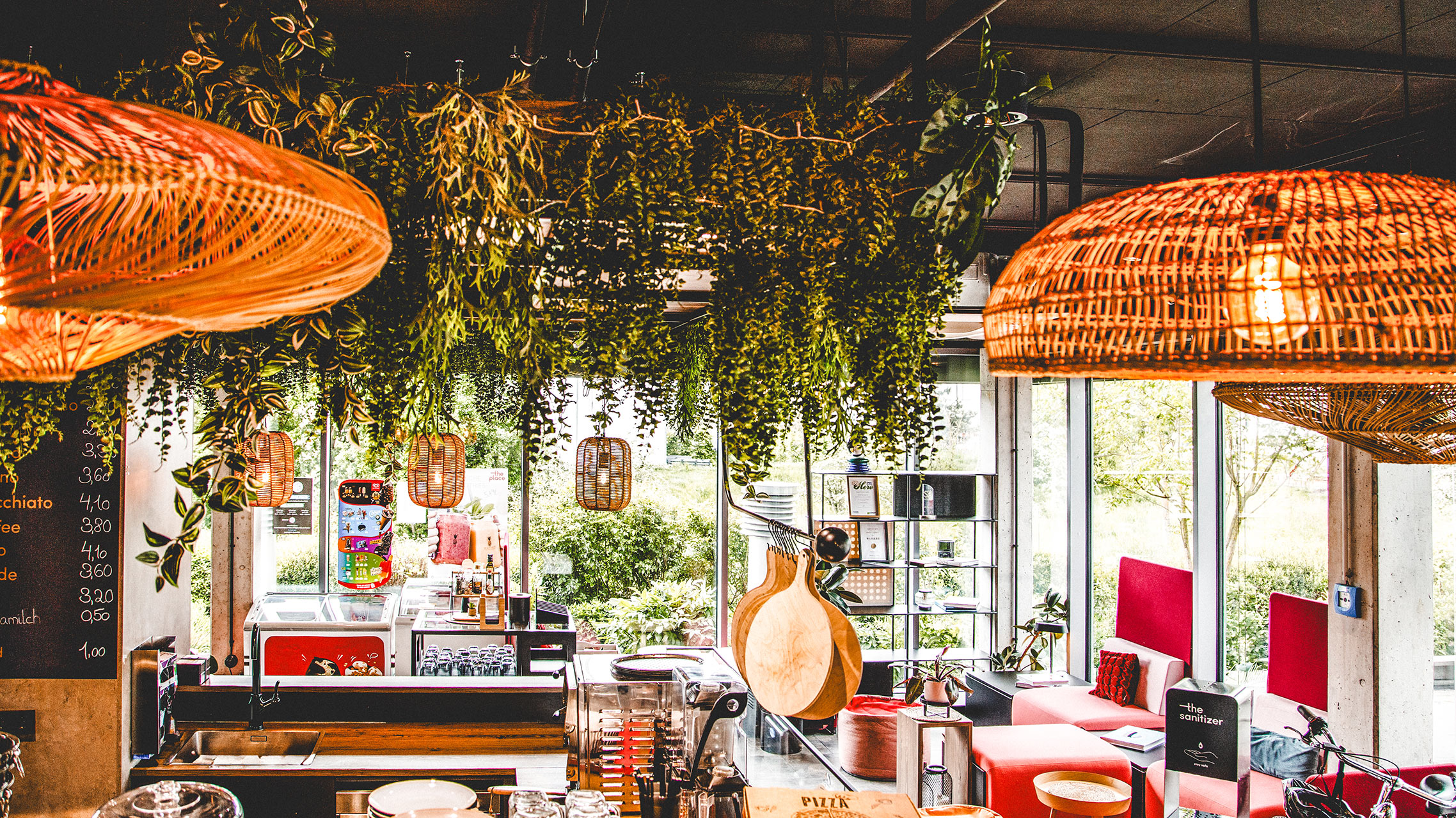 Café-Bar mit hängender Pflanzenbegrünung, Rattan-Leuchten und Kaffeetheke