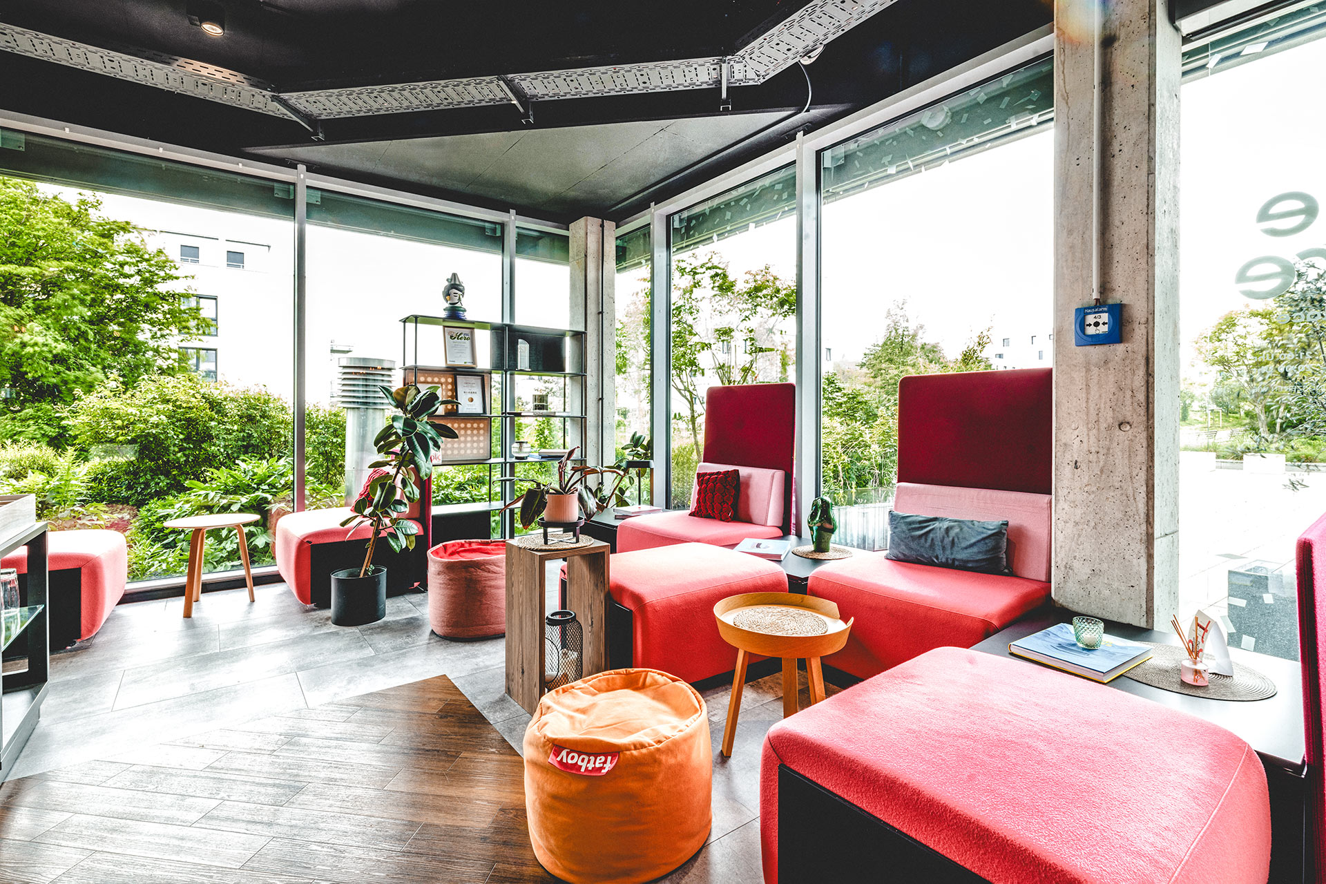 Lichtdurchfluteter Loungebereich in the store mit roten Polstermöbeln und Blick ins Grüne