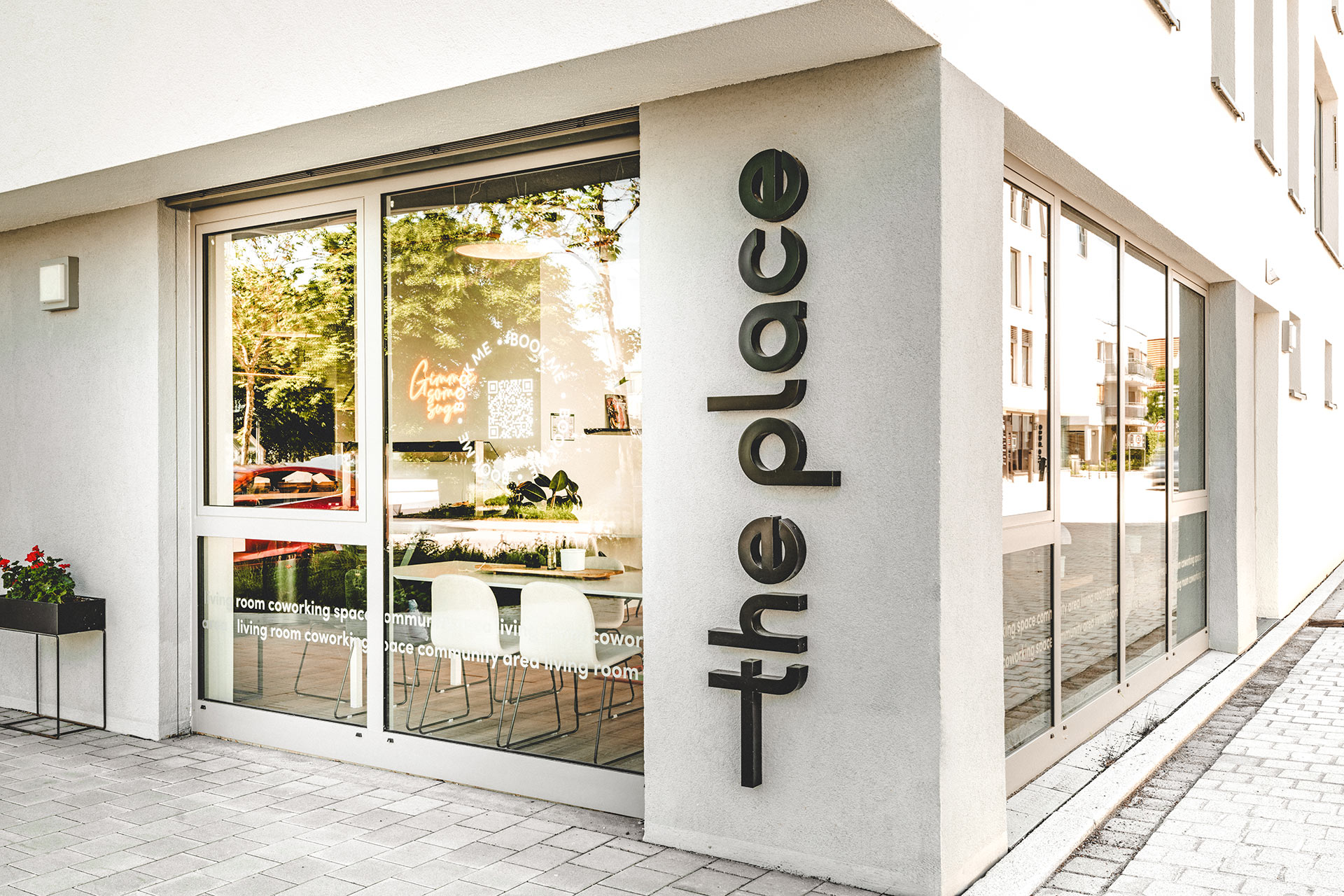 Gebäudeecke mit "the place"-Schriftzug und Einblick in Coworking-Bereich hinter Glasfronten