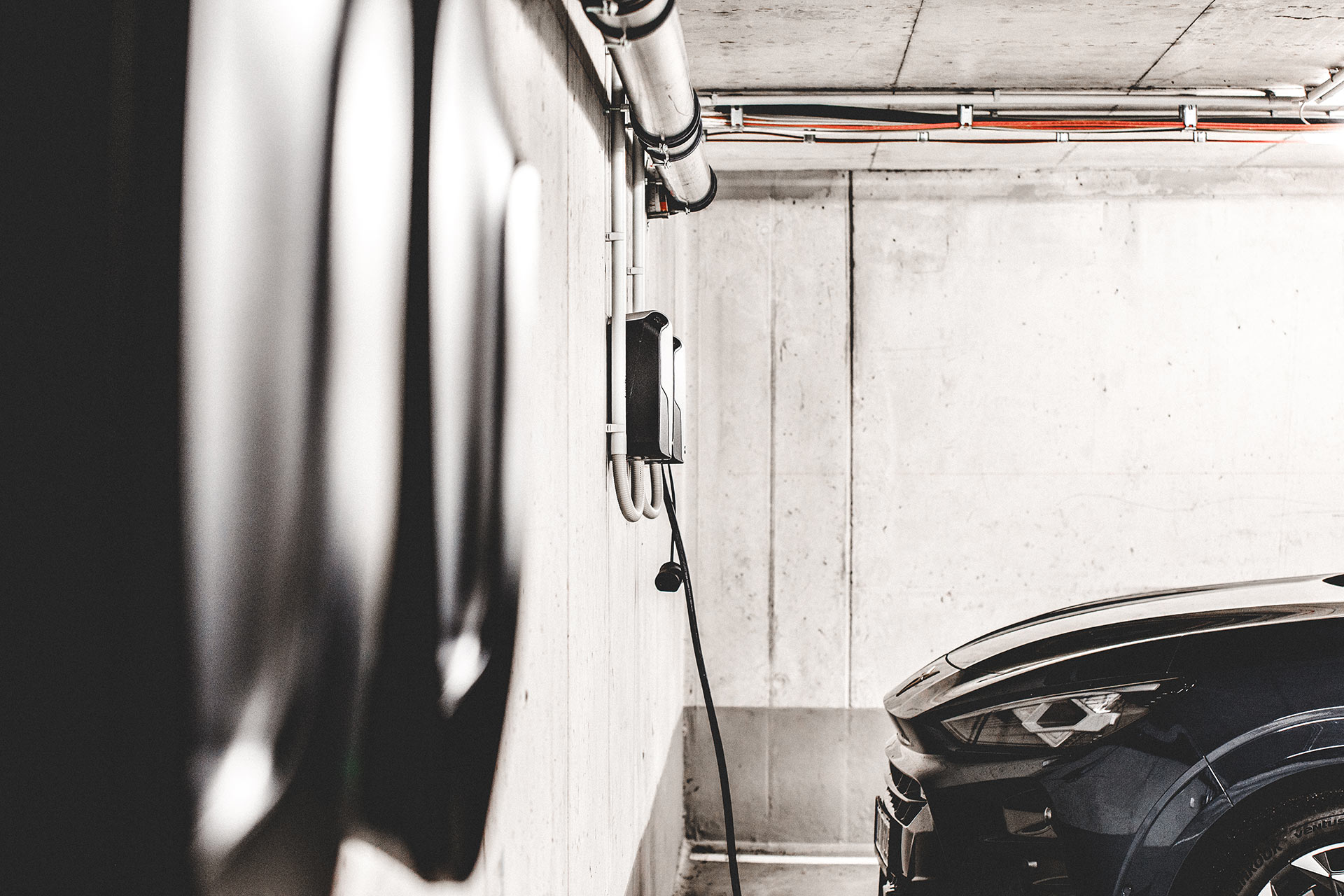 E-Auto-Ladestation in der Tiefgarage mit Kabelverlegung und parkendem Elektrofahrzeug